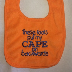 These fools put my cape on backwards embroidered bib