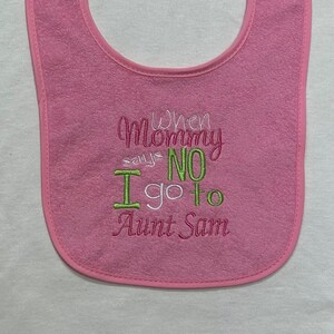 Puede incluir: Babero rosa para bebé con el texto bordado "Cuando mamá dice NO, voy a casa de la tía Sam".
