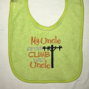 May include: A lime green baby bib with the text "My Uncle can out CLIMB your Uncle" embroidered in orange and black. The embroidery includes a black silhouette of a utility pole with crossbars.