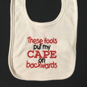 These fools put my cape on backwards embroidered bib