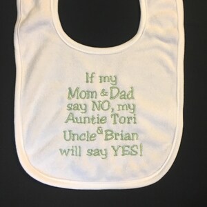 Puede incluir: Babero blanco para bebé con bordado verde que dice "Si mi mamá y mi papá dicen NO, mi tía Tori y mi tío Brian dirán SÍ!"