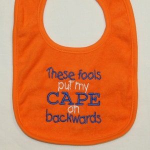 These fools put my cape on backwards embroidered bib