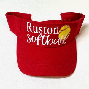 May include: Red visor with a white softball graphic and the text "Ruston Softball".
