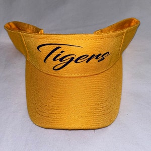 May include: A yellow visor with a black cursive "Tigers" logo.