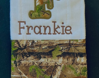 Op de afbeelding: Een witte spuugdoek met een bruin camouflagepatroon op de onderste helft. De bovenste helft heeft een bruine geborduurde letter "F" met een camouflagepatroon in de letter en de naam "Frankie" geborduurd onder de letter.