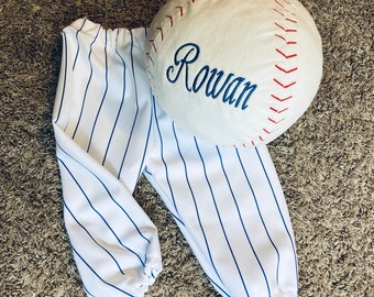 May include: White and blue striped pants with a white baseball with red stitching and the name "Rowan" embroidered on it.