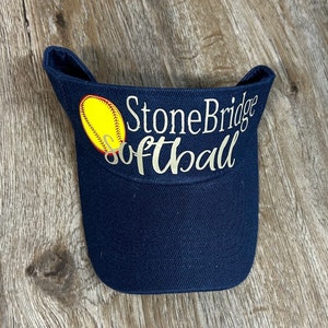 May include: A navy blue visor with a yellow softball and the text "StoneBridge Softball" in silver lettering.