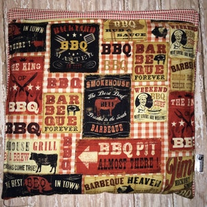 May include: A red and white checkered fabric with a variety of colorful patches featuring BBQ-themed text and images. The patches include phrases like "Backyard BBQ Master", "Smokehouse Barbeque", "BBQ Pit Almost There", and "Barbeque Heaven".