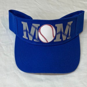 May include: A royal blue baseball visor with a white baseball and the word "MOM" in gray letters with white stitching around the letters.
