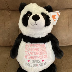 May include: Black and white panda plush toy with a white embroidered heart on its chest. The text on the heart reads "Grampa" with two pink hearts on either side. The text below the heart reads "Uncle Brian Uncle Will". The panda is wearing a white bib with the following text: "Hugs sent from heaven found deep inside to always remind you we're here by your side."