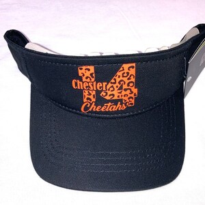 May include: Black visor with a white brim and an orange and black cheetah print design that says "Chester 14 Cheetahs".