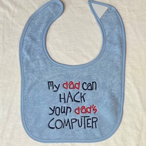 Peut inclure: Une bavette pour bébé de couleur bleu clair avec le texte brodé "My dad can HACK your dad's COMPUTER" en fil rouge et bleu.