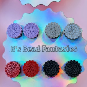 May include: Assortment of colourful, patterned, round, resin earrings. The earrings are displayed on a holographic background with the text "B's Bead Fantasies".