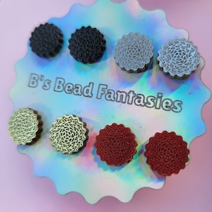 May include: A close-up of eight small, round, decorative, resin earrings in various colours and patterns. The earrings are displayed on a holographic background with the text "B's Bead Fantasies".