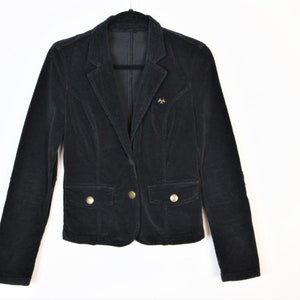 May include: Black corduroy blazer with a notched lapel, two front pockets, and gold-colored buttons. The blazer has a tailored fit and a small gold emblem near the left lapel. The jacket is hanging on a black hanger against a white background.