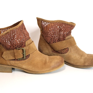 May include: A pair of brown suede ankle boots with a mesh panel and a buckle closure.