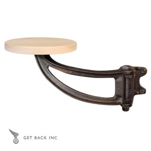 May include: A black metal swivel bar stool with a wooden seat. The stool is mounted to a wall and has a curved arm.
