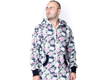 Pode incluir: Uma pessoa vestindo um macacão de estampa floral azul e branco com fecho de zíper e capuz. O macacão tem acabamento preto ao redor dos bolsos e punhos.