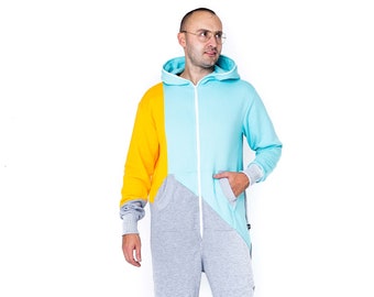 Pode incluir: Uma pessoa vestindo um macacão com capuz cinza, azul e amarelo. O macacão tem um zíper na frente e um bolso na perna esquerda.