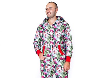 Pode incluir: Um macacão comprido com estampa floral com cactos e flores em tons de rosa, verde e branco. O macacão tem um fecho de correr e um capuz.