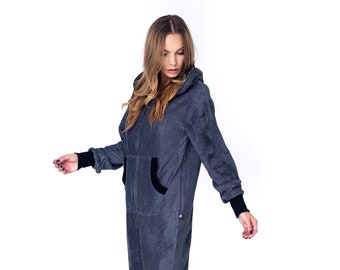 May include: A gray hooded jumpsuit with black trim. The jumpsuit has a zipper closure and pockets. The model is wearing the jumpsuit and is standing on a white background.