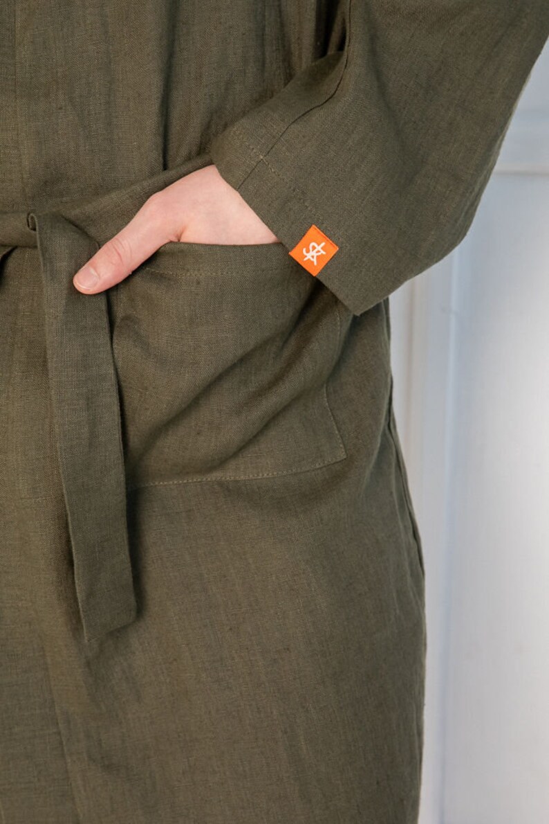 Op de afbeelding: Een groene linnen badjas met een opgestikte zak aan de linkerkant. De zak heeft een klein oranje label met de letters "S&" erop.