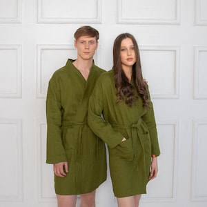May include: Two people wearing matching green robes with long sleeves and a sash at the waist. The robes are made of a soft, textured fabric.