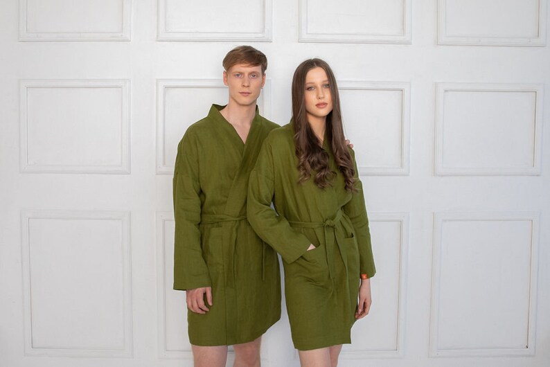 May include: Two people wearing matching green robes with long sleeves and a sash at the waist. The robes are made of a soft, textured fabric.