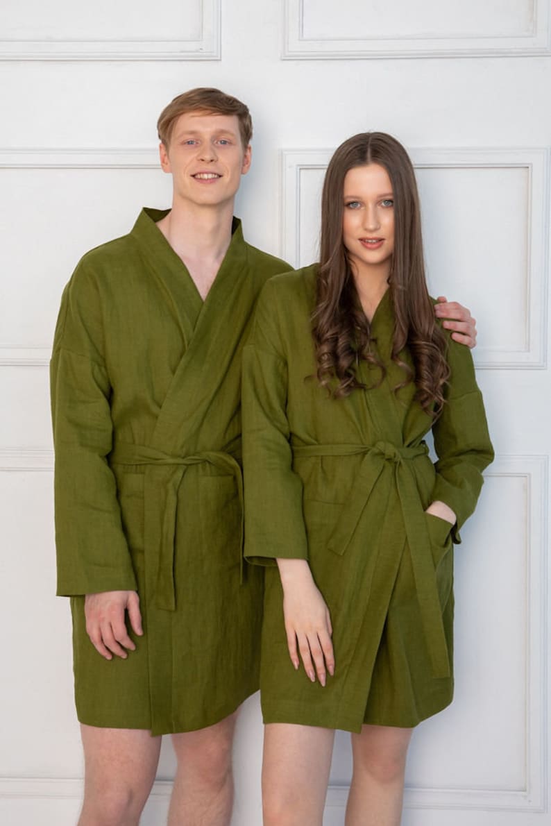 May include: Two people wearing matching olive green linen robes. The robes have a shawl collar and a tie belt.
