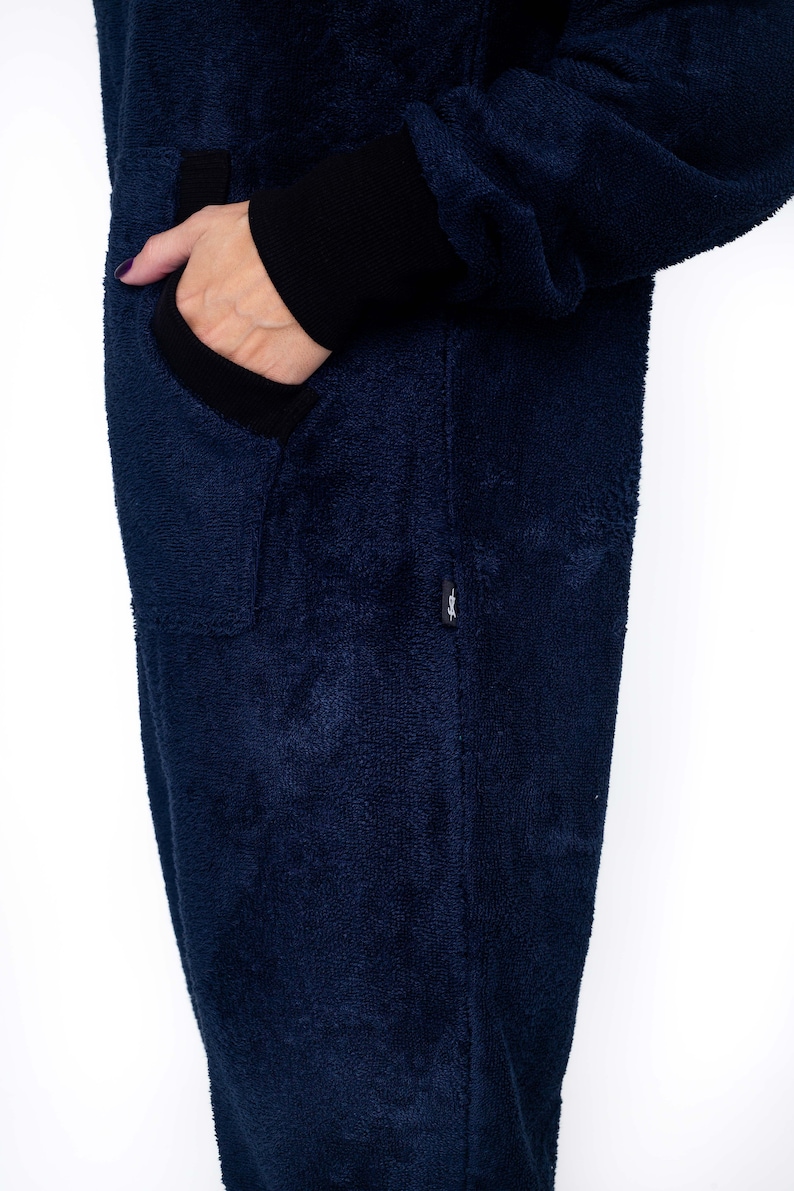 May include: A dark blue fleece jumpsuit with a black zipper and a black pocket on the left side.