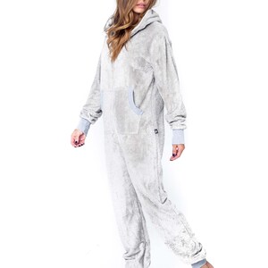 May include: A grey hooded onesie with a zip fastening and pockets. The onesie is made from a soft, fluffy material.