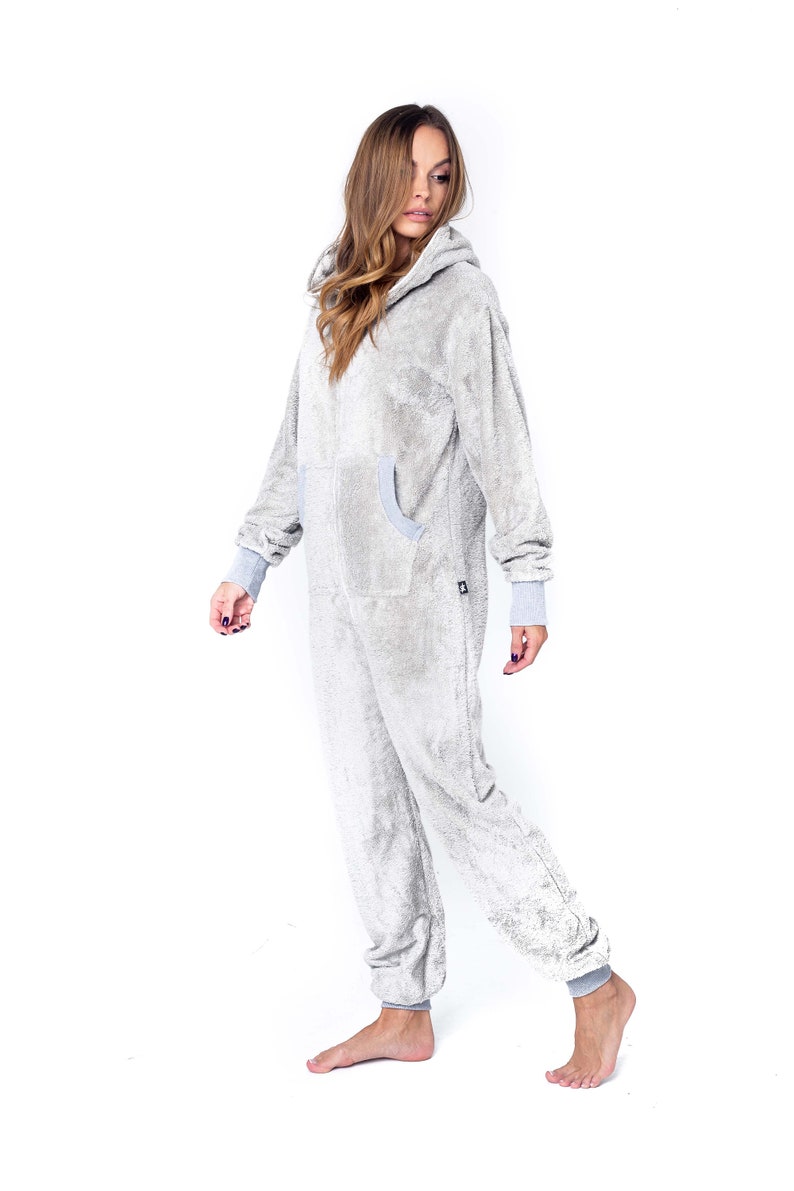 May include: A grey hooded onesie with a zip fastening and pockets. The onesie is made from a soft, fluffy material.