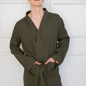 Op de afbeelding: Een donkergroene linnen badjas met een zelfbindende riem en twee zakken. De badjas heeft een ontspannen pasvorm en een shawlkraag.