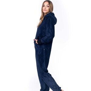 May include: A dark blue hooded jumpsuit with a zipper closure. The jumpsuit has a relaxed fit and is made of a soft, plush fabric.