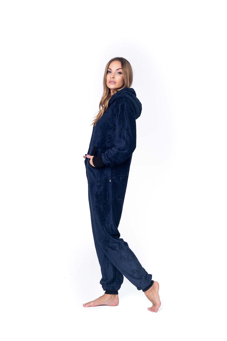May include: A dark blue hooded jumpsuit with a zipper closure. The jumpsuit has a relaxed fit and is made of a soft, plush fabric.