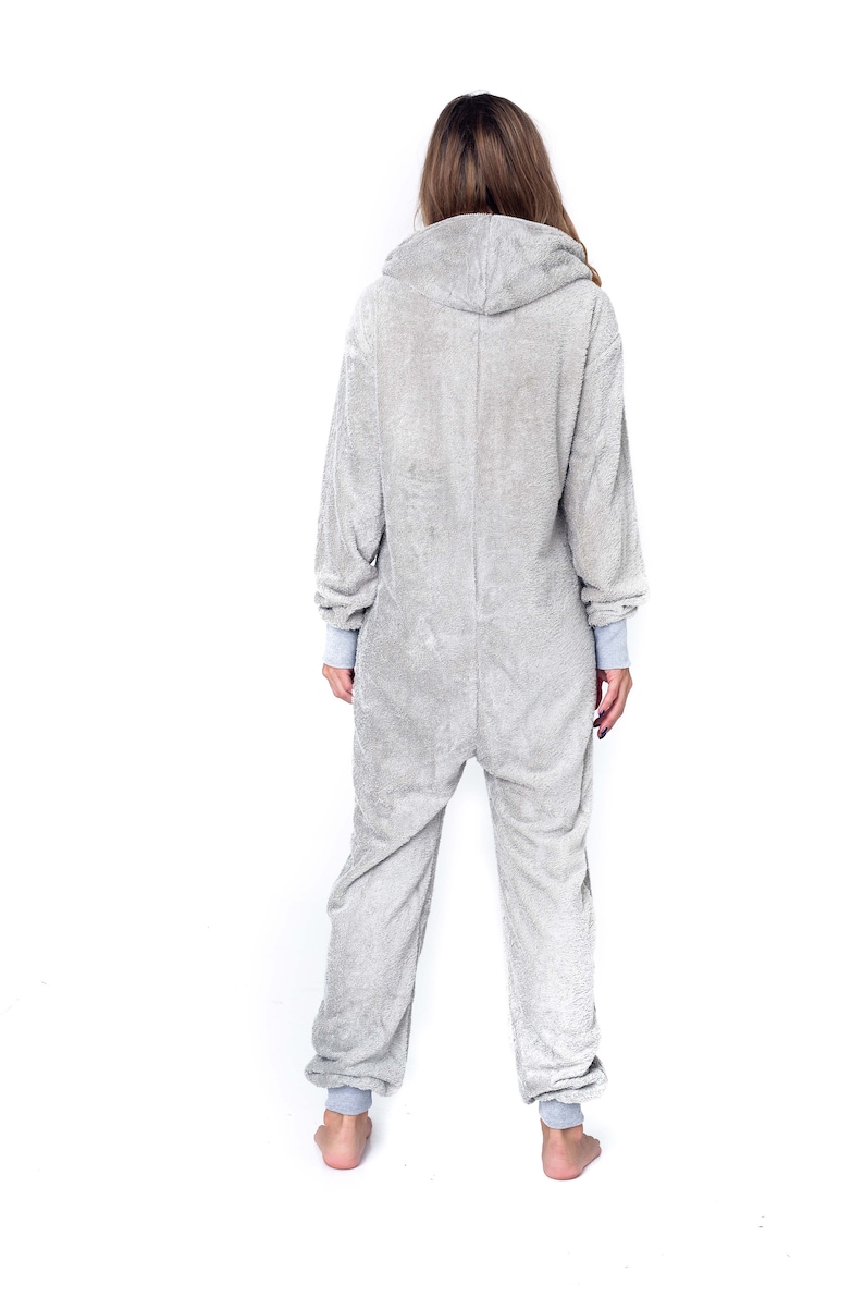 May include: A grey hooded onesie with long sleeves and a zip closure. The onesie is made of a soft, fuzzy material.