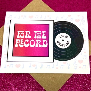 May include: A white card with a pink and red gradient background. The card has a black and white vinyl record on the right side with the text "You're Really Hot" on it. The left side of the card has the text "For The Record" in a retro font.