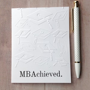 May include: White card with a pattern of graduation caps and the text "MBA Achieved."