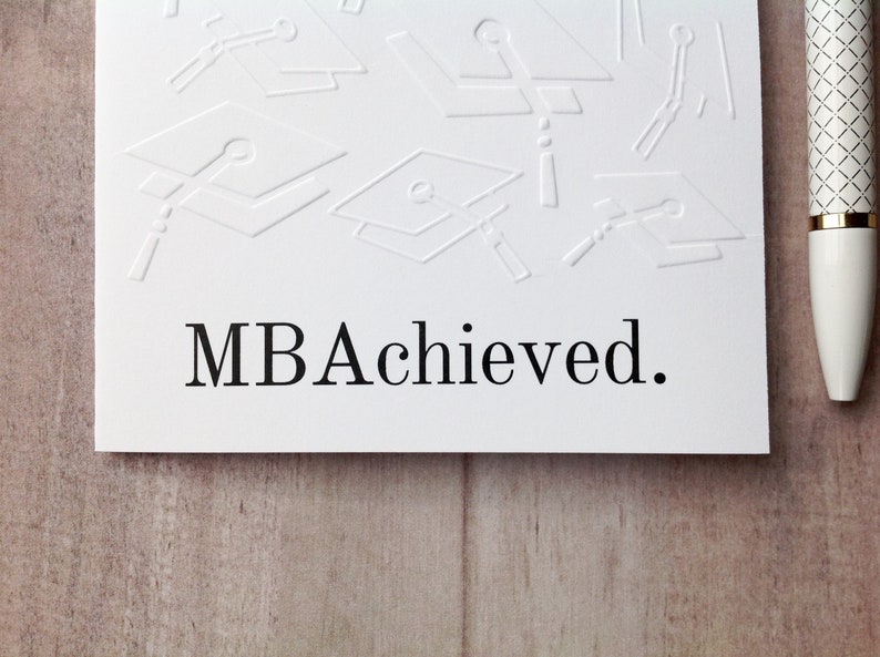 May include: White card with an embossed design of graduation caps and the text "MBA Achieved."