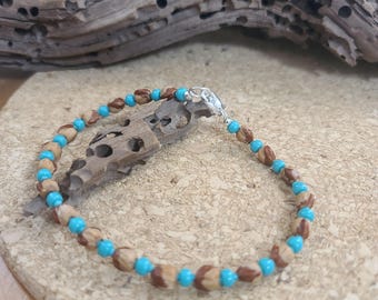 May include: A beaded bracelet featuring alternating small turquoise blue round beads and larger brown textured natural seed beads. The bracelet is secured with a silver-toned metal lobster claw clasp, creating a circular design with a repeating pattern.