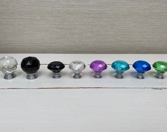 Puede incluir: Surtido de diez pomos de armario de cristal en forma de diamante en varios colores, incluyendo transparente, negro, morado, azul y verde. Los pomos tienen una base plateada.
