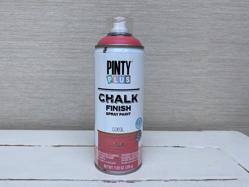 May include: A can of Pinty Plus Chalk Finish spray paint in coral. The can is white with a pink top and features the brand name and product description. The net weight is 335 g.