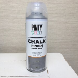 May include: A can of Pinty Plus Chalk Finish spray paint in Ash Grey. The label displays the brand and product information. The can is grey with a clear plastic cap, set against a neutral backdrop.