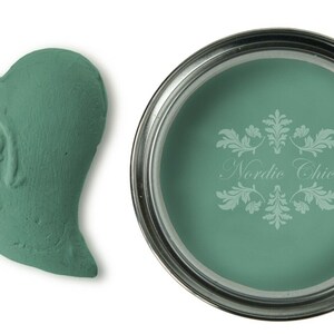 May include: A teal green paint sample in a heart shape and a can of teal green paint with the text "Nordic Chic" on the label.