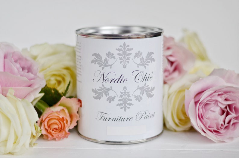 Puede incluir: Una lata blanca de pintura para muebles Nordic Chic con tapa plateada y un dise&ntilde;o floral plateado en la etiqueta.