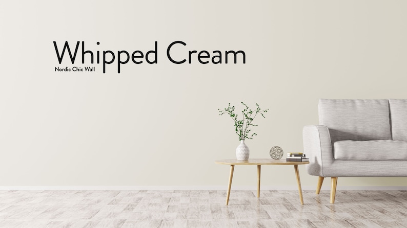 May include: A living room interior design with a light gray sofa, a wooden coffee table, a vase with green plants, and a white wall with the text "Whipped Cream Nordic Chic Wall".