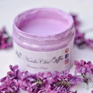 K&ouml;nnte beinhalten: Ein Glas mit helllila Farbe, beschriftet mit "Nordic Chic" M&ouml;belfarbe.