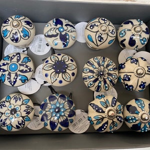 以下が含まれることがあります： 青と白のフローラルパターンが施されたセラミックノブが12個。ノブの中央には銀色の金属アクセントがあります。