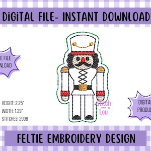 May include: A digital feltie embroidery design of a toy soldier nutcracker. The design is white with red and gold accents, and the text "DIGITAL FILE - INSTANT DOWNLOAD" is at the top. The design is 2.25 inches high and 1.29 inches wide.