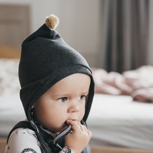 Cappello da bambino grigio scuro con pompon di senape, cappello da nano per neonato, cappello da pilota per neonato in cotone organico, cappello a cuffia per neonato, primo cappello da neonato, cappello legato immagine 1